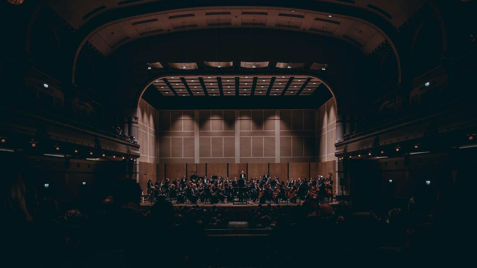 Ein Orchester spielt auf einer großen Theaterbühne im warmen Scheinwerferlicht